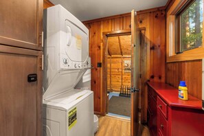 A laundry room with a washer and dryer, wooden walls, a red cabinet, and a window. - Bearfoot Cabin - Central Tahoe Cabin (South Lake Tahoe)