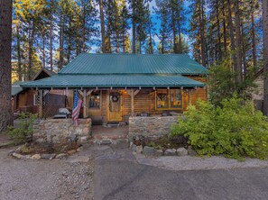 A rustic cabin with a green metal roof, stone foundation, and a wooden front door. - Bearfoot Cabin - Central Tahoe Cabin (South Lake Tahoe)