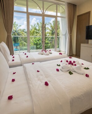 A hotel room with two beds, a large window with a view of palm trees, and a television on the wall. - Waterside Maldives  (Dhidhdhoo)