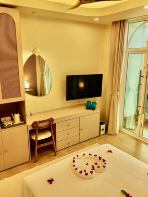 A hotel room with a bed, a television, a wardrobe, a chair, and a window with curtains.