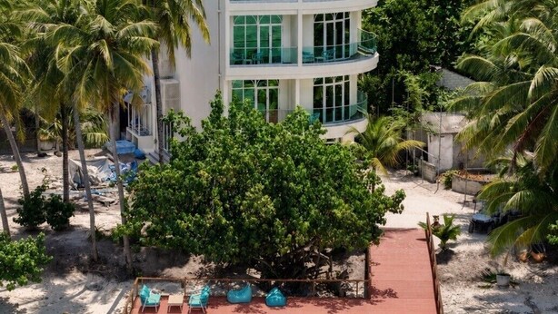 Un immeuble à plusieurs étages doté d’une piscine et d’un espace extérieur aménagé pour s’asseoir.