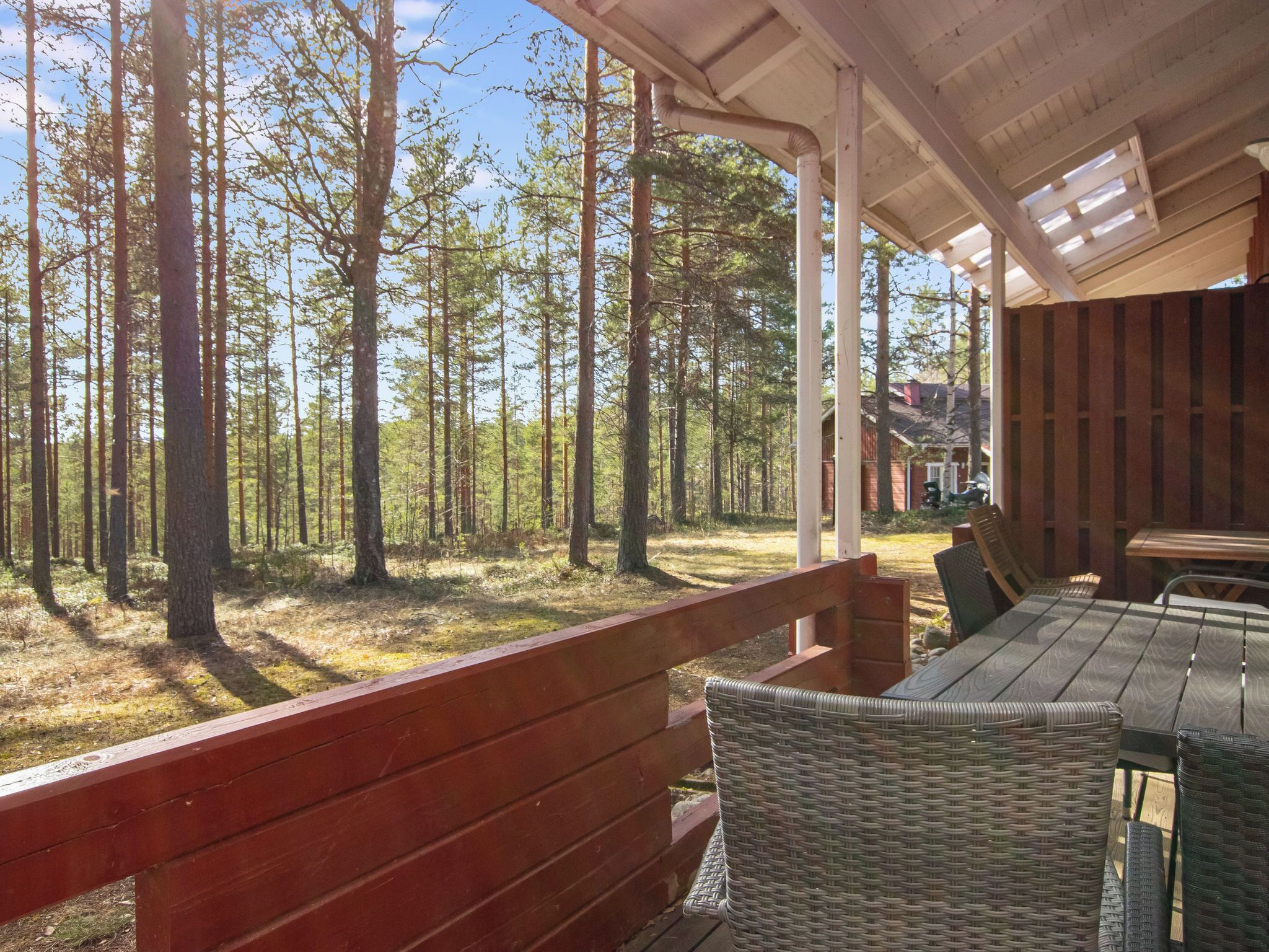 A covered outdoor seating area with a view of a forest.