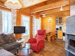 A cozy cabin interior with a living area, a red armchair, a television, and a stone fireplace. - Koli country club b 6 by Interhome (Lieksa)