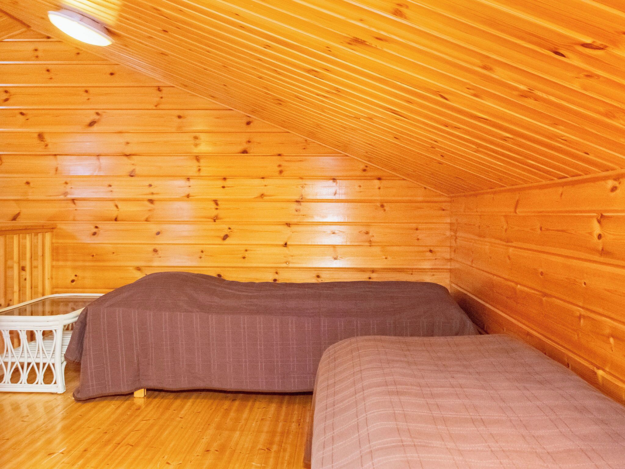 Een chalet met schuine daklijn, houten wanden en twee bedden.
