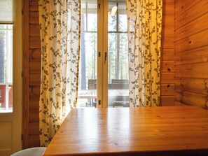 A wooden interior with a large table and curtains with a floral pattern. - Koli country club b 6 by Interhome (Lieksa)