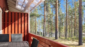 Eine Holzterrasse mit Tisch und Stühlen, mit Blick auf einen Wald.