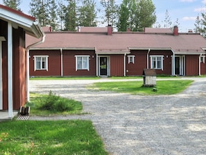 A row of red wooden buildings with a gravel driveway and a grassy area in front. - Koli country club b 7 by Interhome (Lieksa)
