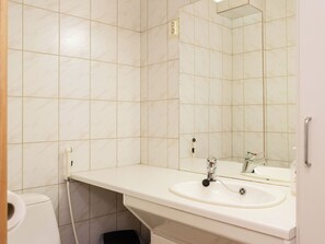Een badkamer met een witte wastafel, spiegel en betegelde wanden.