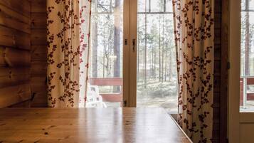 Ein Holztisch in einem Zimmer mit Blick auf einen Wald durch eine Glastür.
