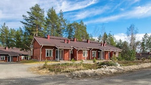 En rad röda trähus med tillhörande verandor, omgivna av träd.