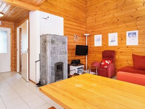 Ein Holzinterieur mit Kamin, Fernseher und einem roten Sofa.