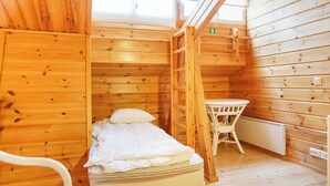 Una camera in una baita di legno con un letto, un tavolo e una sedia.