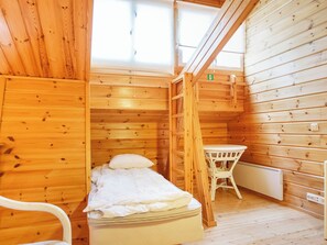 Una habitación de cabaña de madera con una cama, una mesa y una silla.
