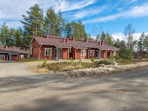 A row of red wooden cabins with attached porches, surrounded by trees. - Koli country club d 13 by Interhome (Lieksa)