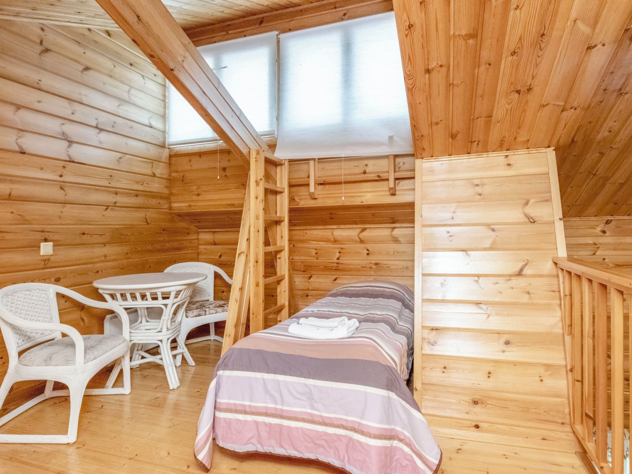 A cozy cabin room with a bed, a table, and two chairs.
