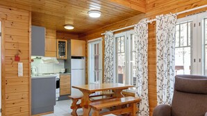 Ein Holzblockhaus-Interieur mit Küche, Essbereich und einer Couch.