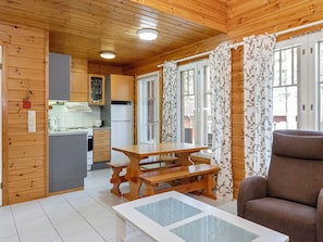 A wooden cabin interior with a kitchen, dining area, and a sofa. - Koli country club d 13 by Interhome (Lieksa)