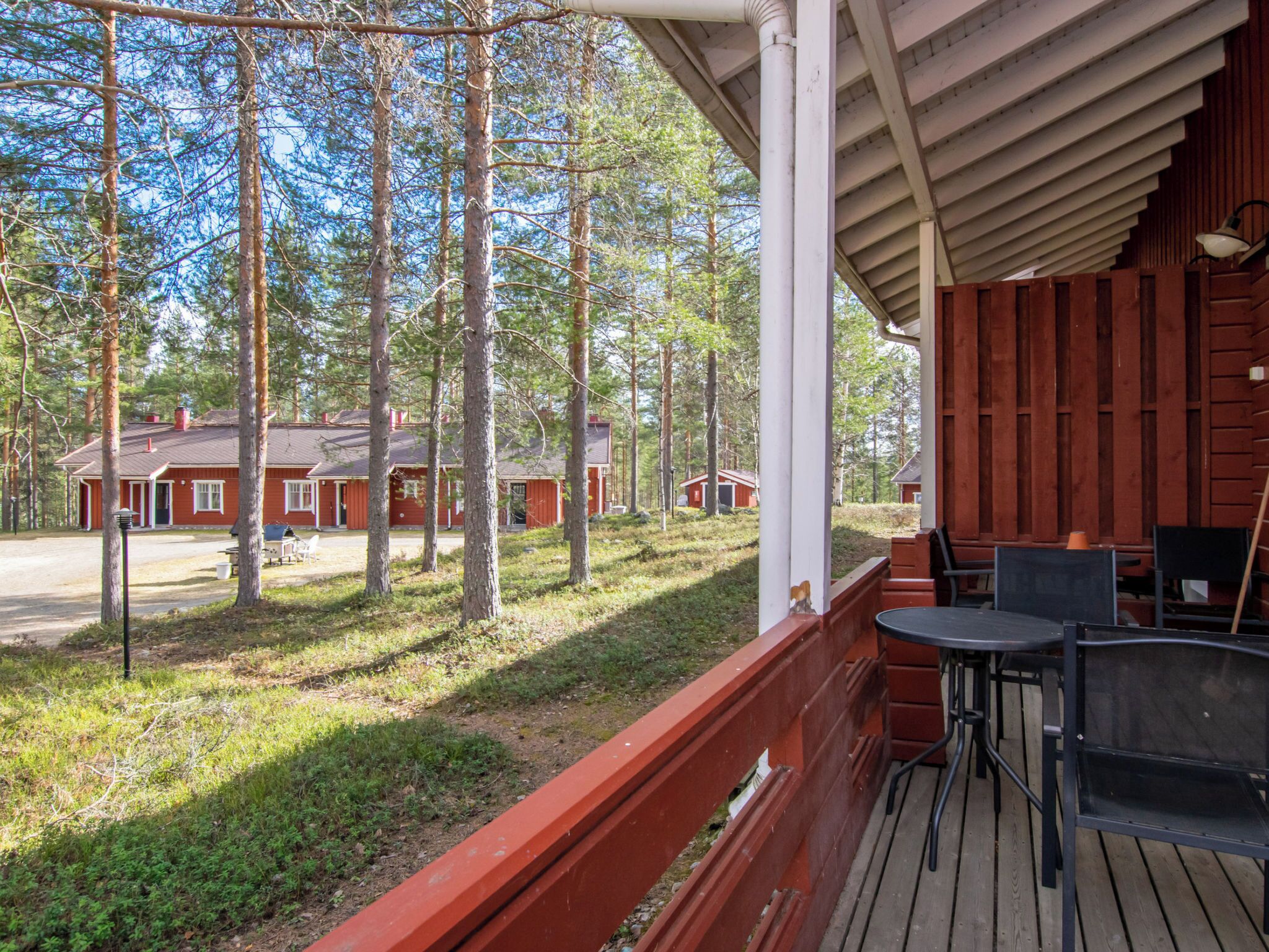 Eine HolzdTerrasse mit Sitzgelegenheiten im Freien mit Blick auf ein Waldgebiet und Ferienhäuser.