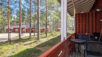 Eine HolzdTerrasse mit Sitzgelegenheiten im Freien mit Blick auf ein Waldgebiet und Ferienhäuser.