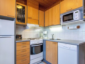 Une cuisine compacte avec des meubles en bois, un four à micro-ondes, une cuisinière et un lave-vaisselle.