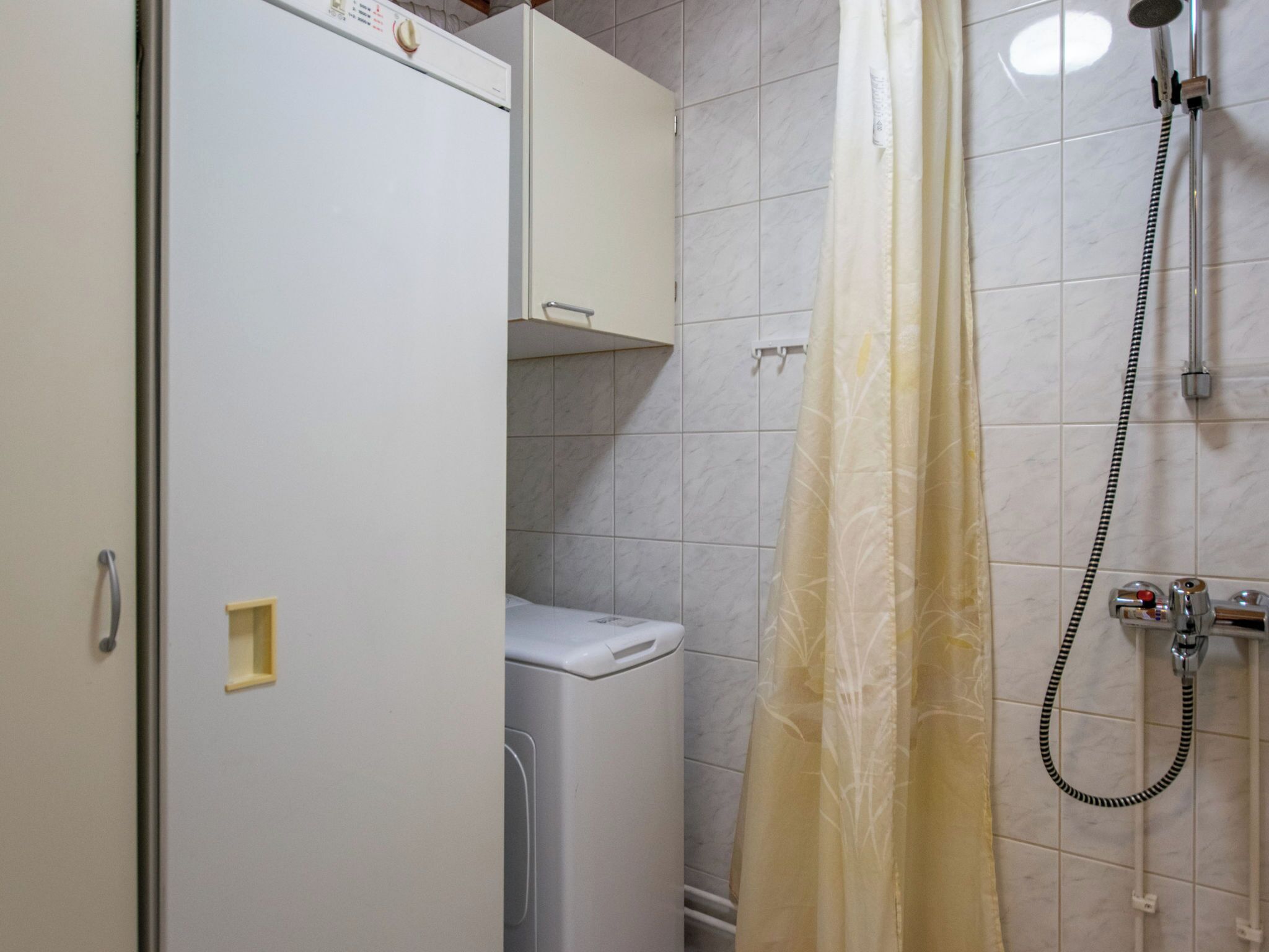 Ein Badezimmer mit Dusche, Toilette und einem weißen Schrank.