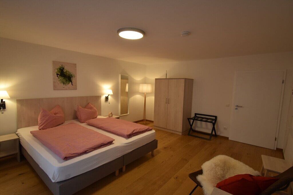 Ein Schlafzimmer mit zwei Betten, einem Kleiderschrank, einem Sessel und einer Lampe.