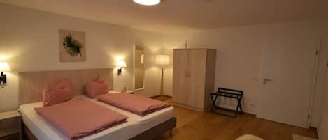 Ein Schlafzimmer mit zwei Betten, einem Kleiderschrank, einem Sessel und einer Lampe.