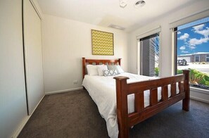 A bedroom with a bed, a window, and a view of the outside.