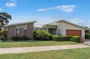 A two-story residential house with a brick facade, a garage, and a well-maintained lawn.