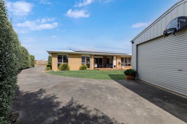 A two-story building with a garage, a covered patio, and a well-maintained lawn.