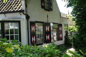 Ein traditionelles Gebäude mit einem Ziegeldach, mehreren Fenstern mit Fensterläden und einer kleinen Veranda.