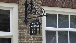 A brick building with a black sign that reads 'Hartje Holland' and a black metal fixture above it.