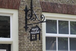 A brick building with a black sign that reads 'Hartje Holland' and a black metal fixture above it.