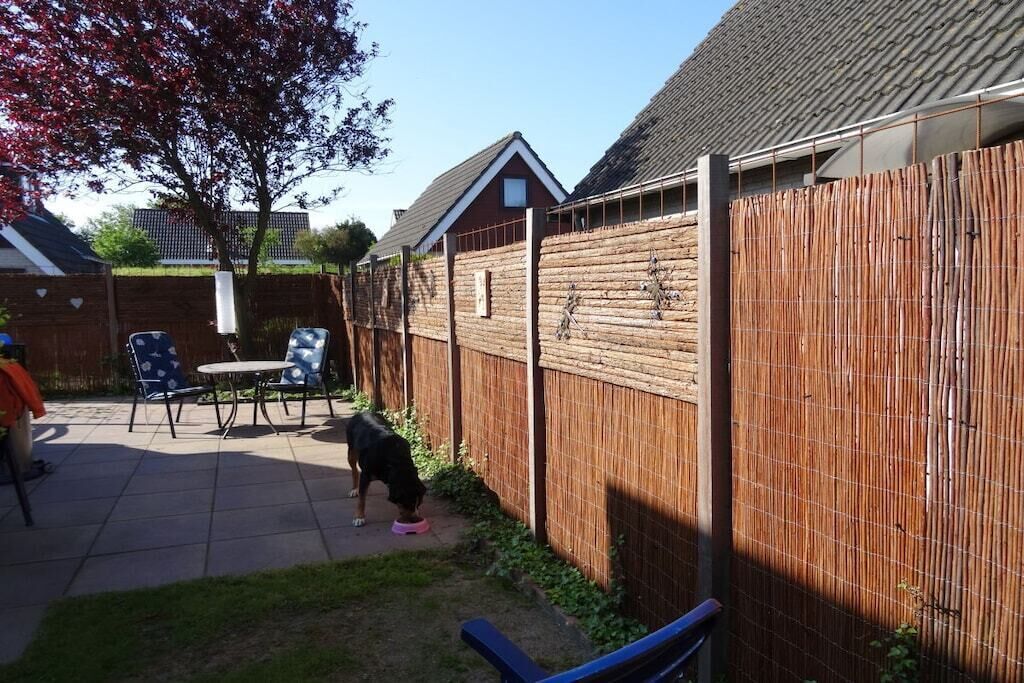 A backyard with a fenced area, a dog, and outdoor furniture.