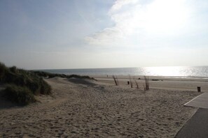 Ein sandiger Strand mit klarem Himmel und dem Ozean im Hintergrund.