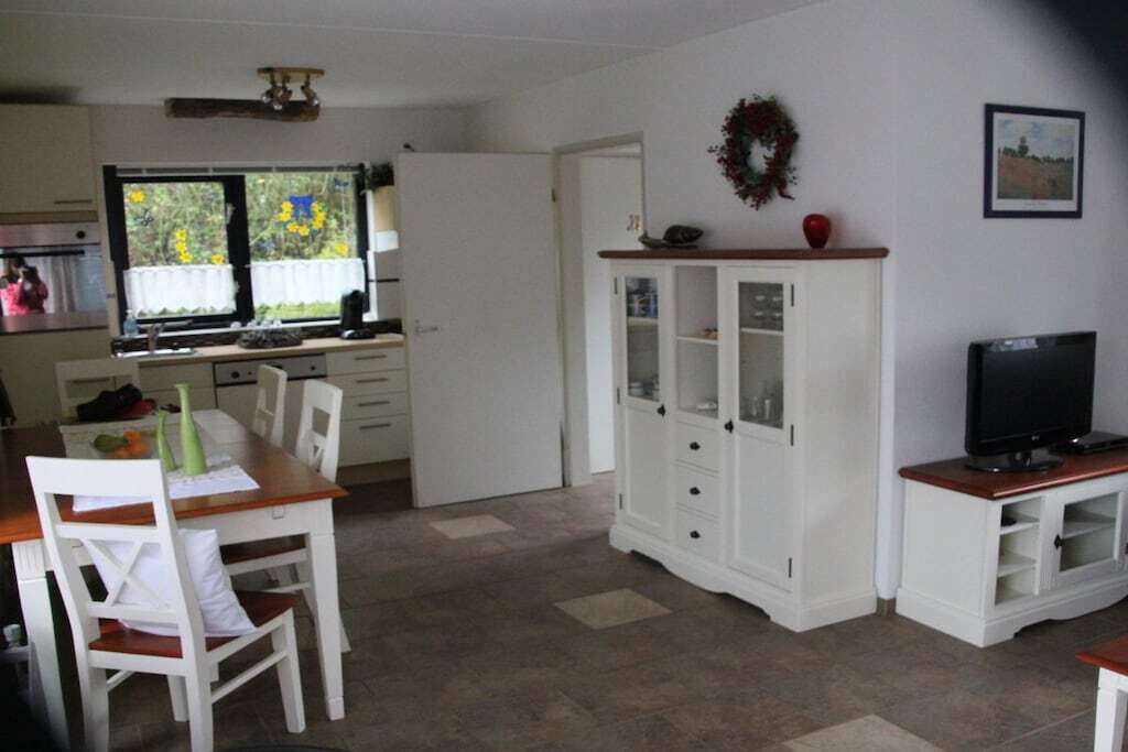 Un espacio habitable compacto con comedor, cocina con ventana, un armario blanco y televisor.