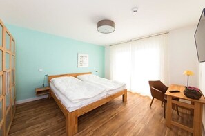 A room with a wooden bed, a desk with a lamp, and a chair. - 11 in the Villa Meeresblau (Cuxhaven)