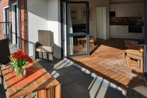An open-plan living area with a dining table, a wicker chair, and a sliding glass door leading to a kitchen. - 11 in the Villa Meeresblau (Cuxhaven)