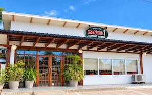 Un hostal McCoy's cerca del aeropuerto, con fachada de madera, ventanas grandes y plantas en macetas al frente.