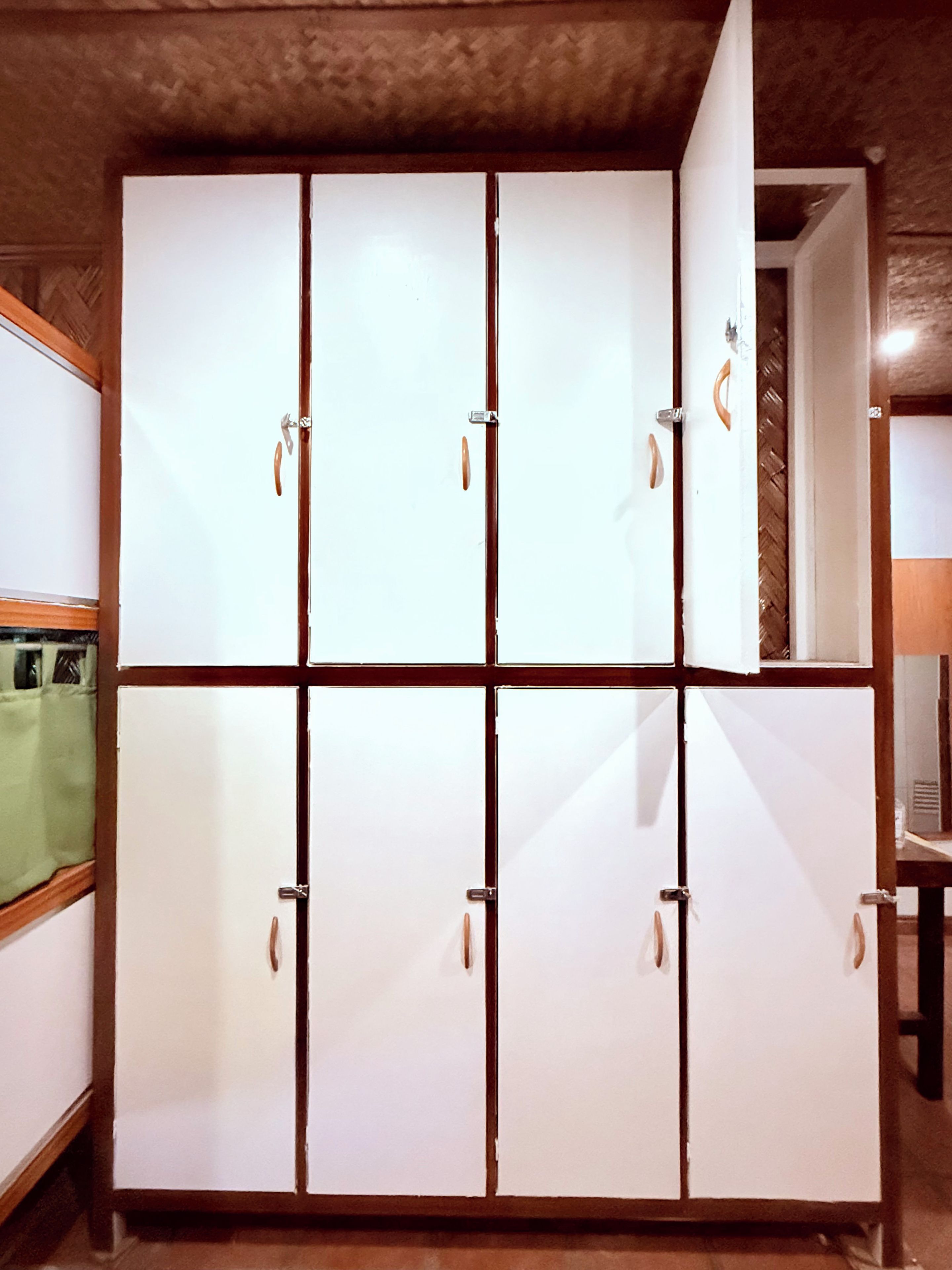 Ein großer Kleiderschrank mit vielen Fächern, einer Holzzieldecke und einem teilweise sichtbaren grünen Vorhang.