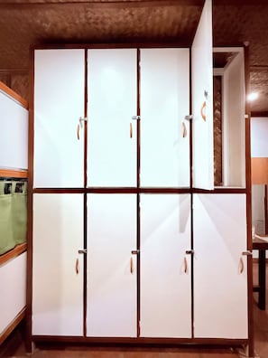 Un armario grande con varios compartimentos, techo de madera y una cortina verde parcialmente visible.