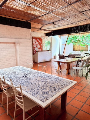 Comedor con una mesa grande, sillas y vistas a un jardín.