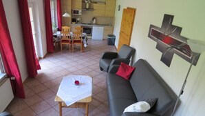 A living room with a sofa, a table, and a kitchen in the background. - 1 on the Grafel farm (Kirchlinteln-Stemmen)
