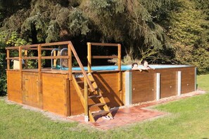 Una estructura de fusta amb una piscina, una escala i una zona coberta amb portes.