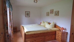 A bedroom with a wooden bed, bedside tables, and a small bench. - 1 on the Grafel farm (Kirchlinteln-Stemmen)