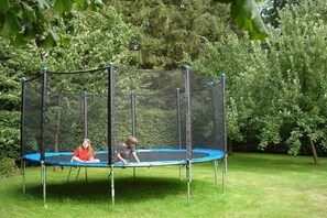 Ein Trampolin mit Sicherheitsnetz in einer grünen Wiese.