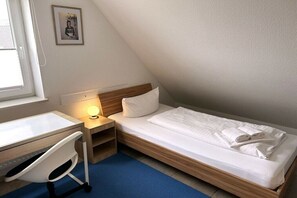 A small, single-bed room with a desk and chair, a bedside lamp, and a framed picture on the wall. - HOUSE LUV 2 - on the upper floor (Wittdün)