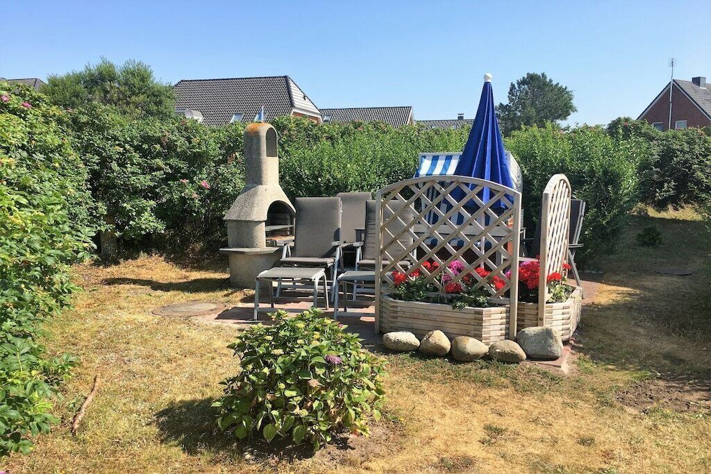 A garden with a barbecue area, a wooden structure with a lattice top, and a small bush.
