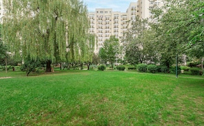 Ein Park mit Gras, Bäumen und einem Gebäude im Hintergrund.