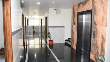A hotel corridor with a polished floor, a potted plant, and an elevator.